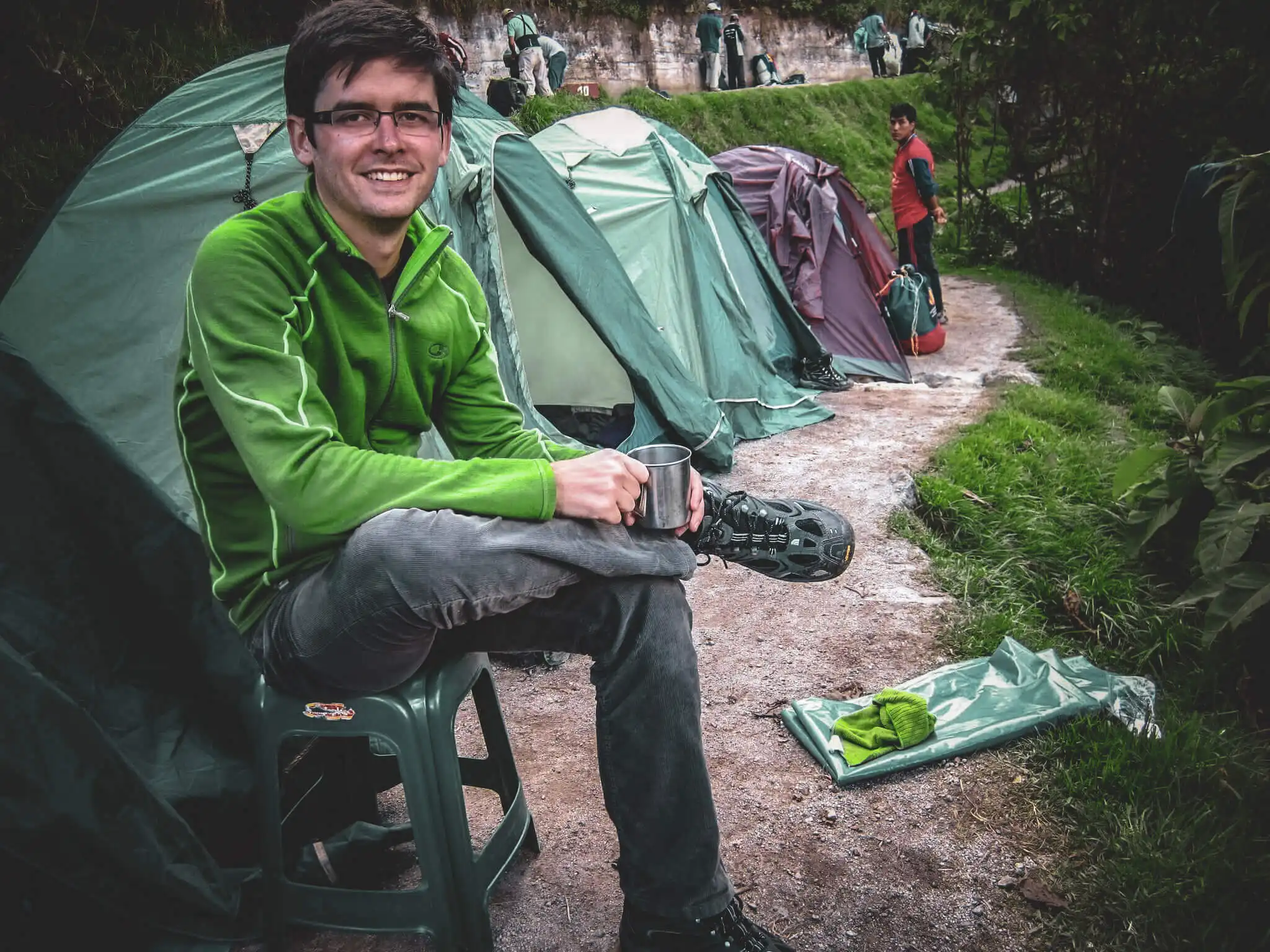 Traveler sitting outside tents at an Inca Trail campsite
