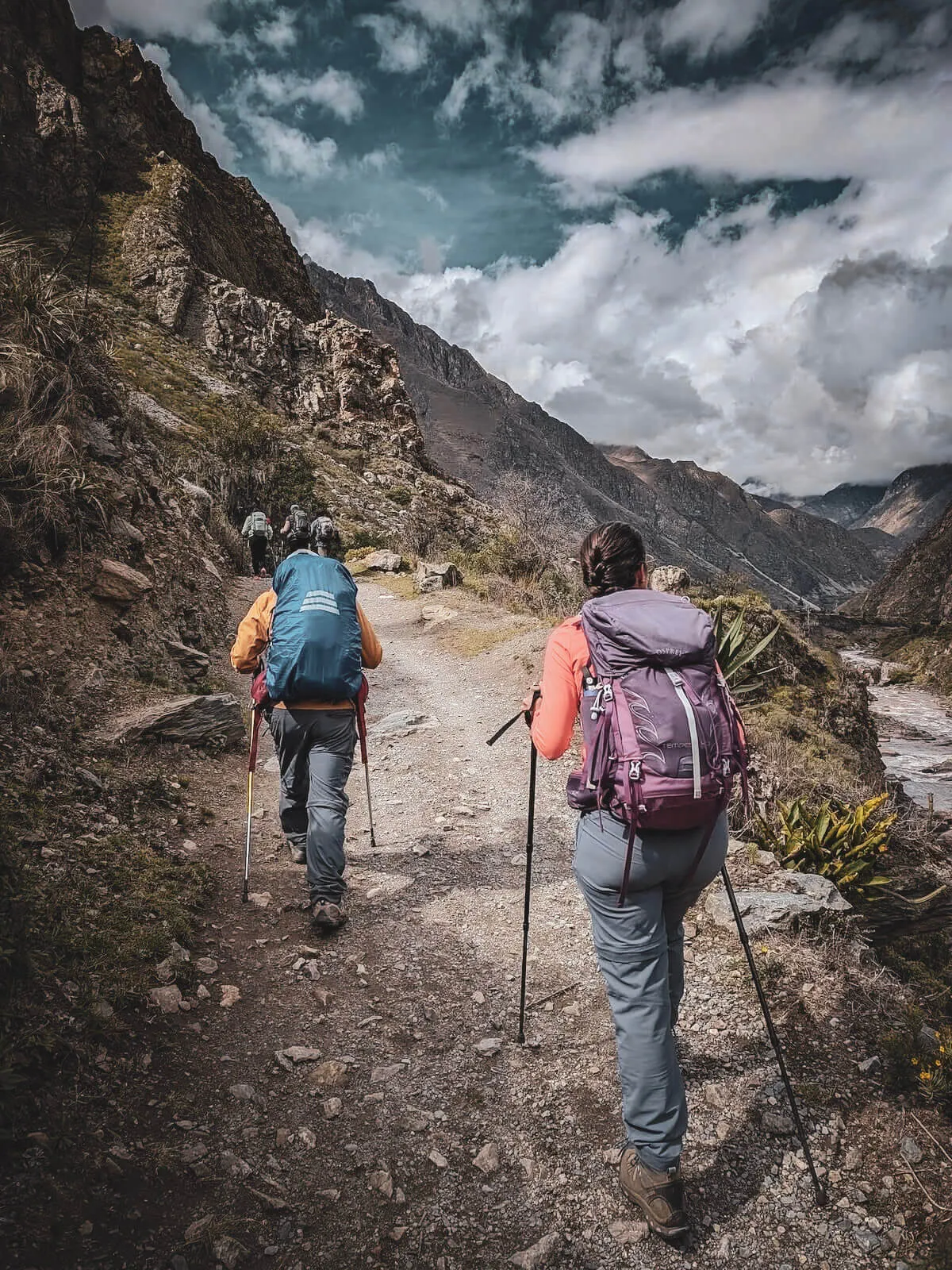 Hikers crossing an exposed mountain trail with secured backpacks