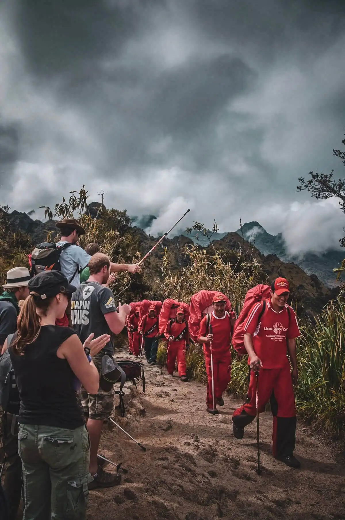 Travelers standing aside while loaded porters pass on the Inca Trail